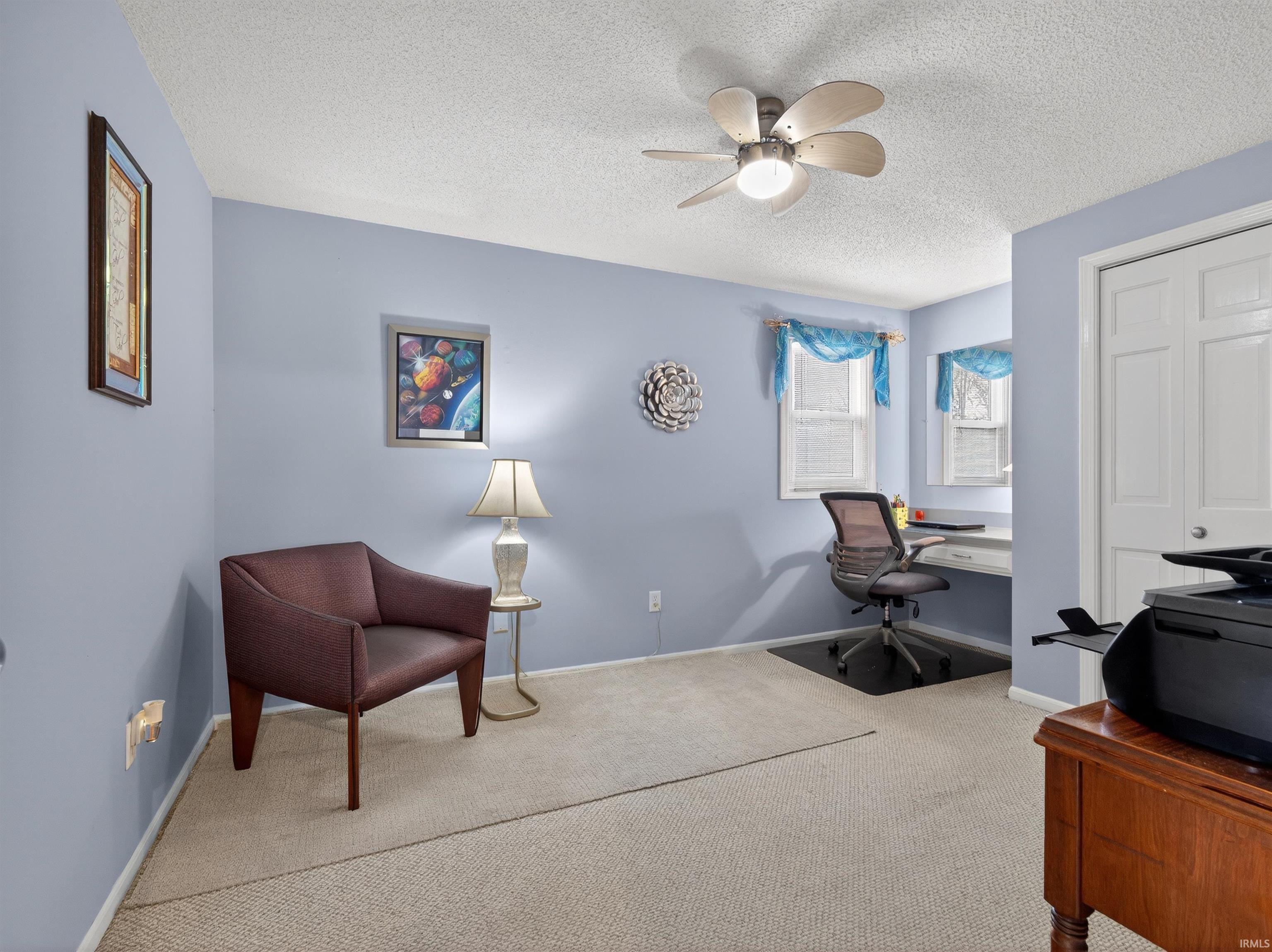 Carpeted office featuring a textured ceiling and ceiling fan