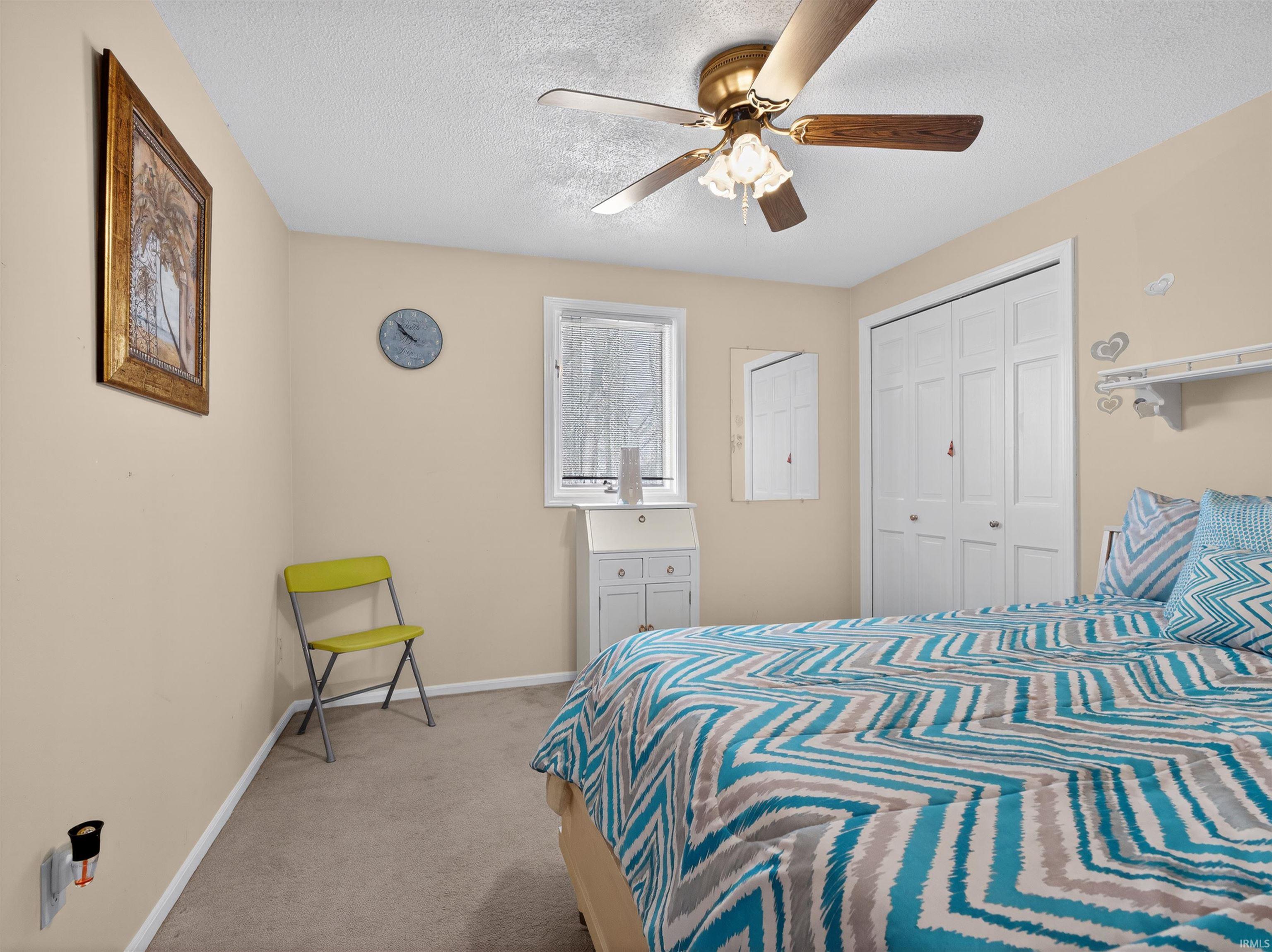 Bedroom featuring light carpet, ceiling fan, a textured ceiling, and a closet