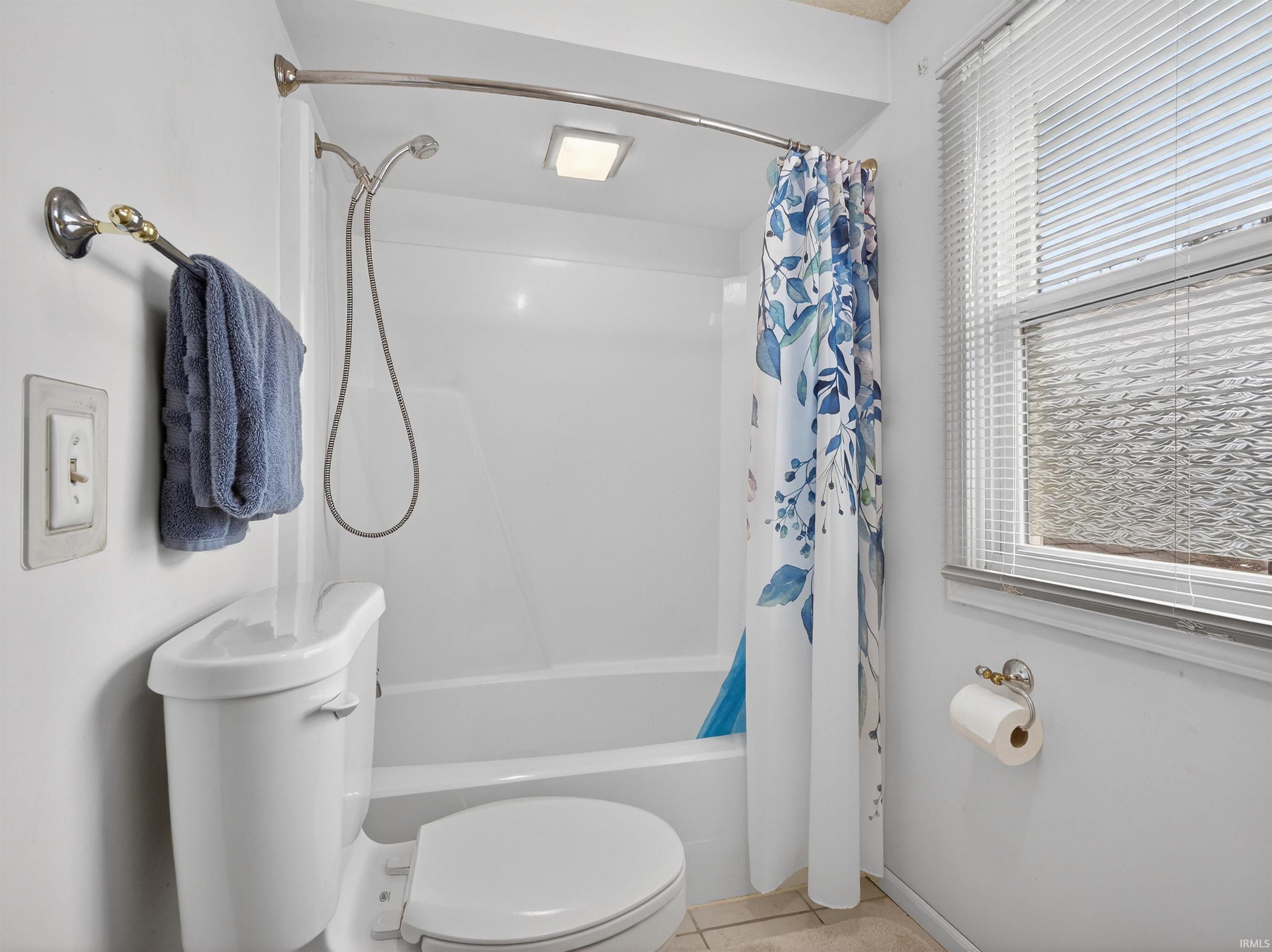 Full bath featuring shower / bathtub combination with curtain and light tile patterned flooring