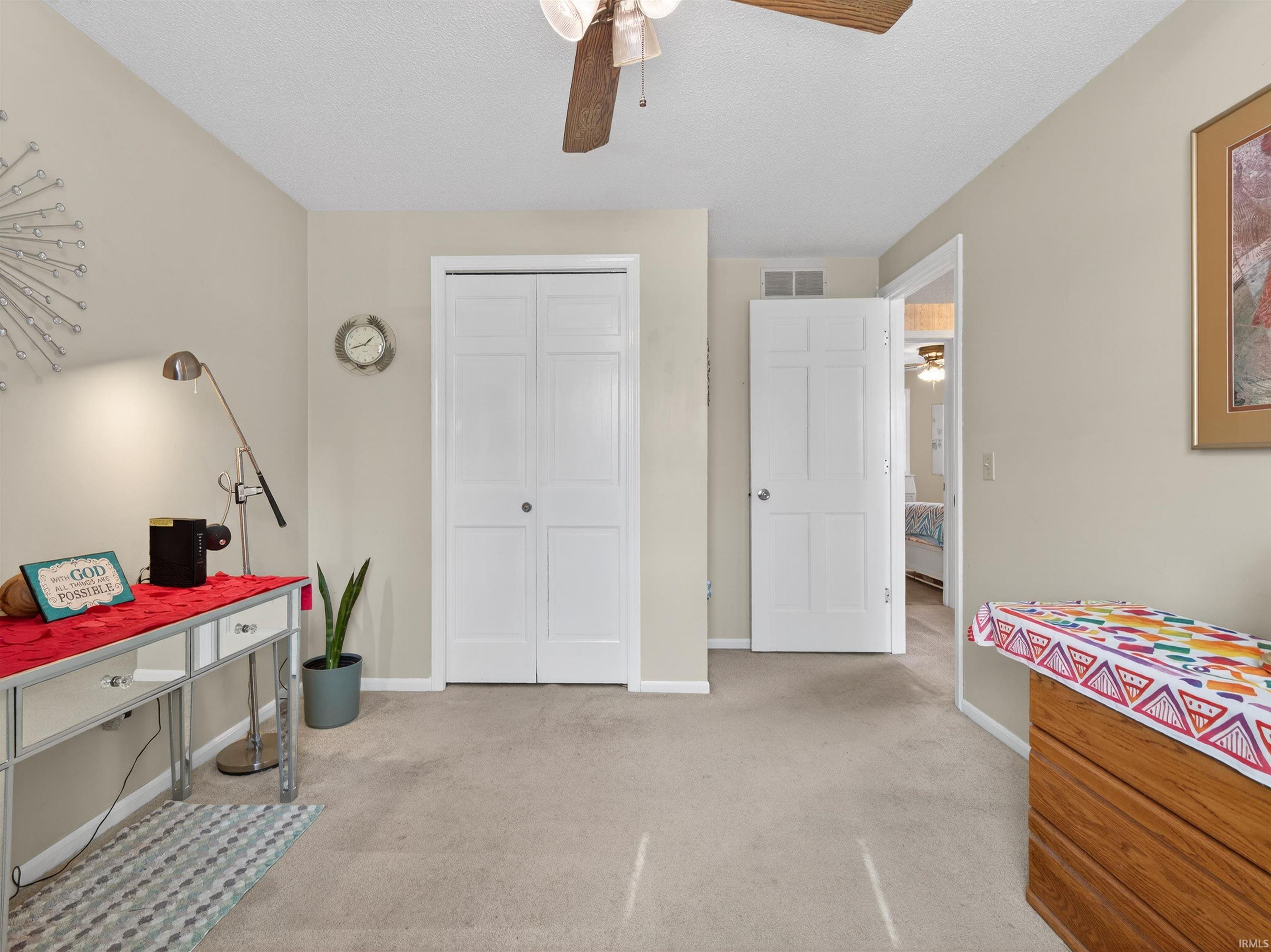 Bedroom featuring light carpet, ceiling fan, and a closet