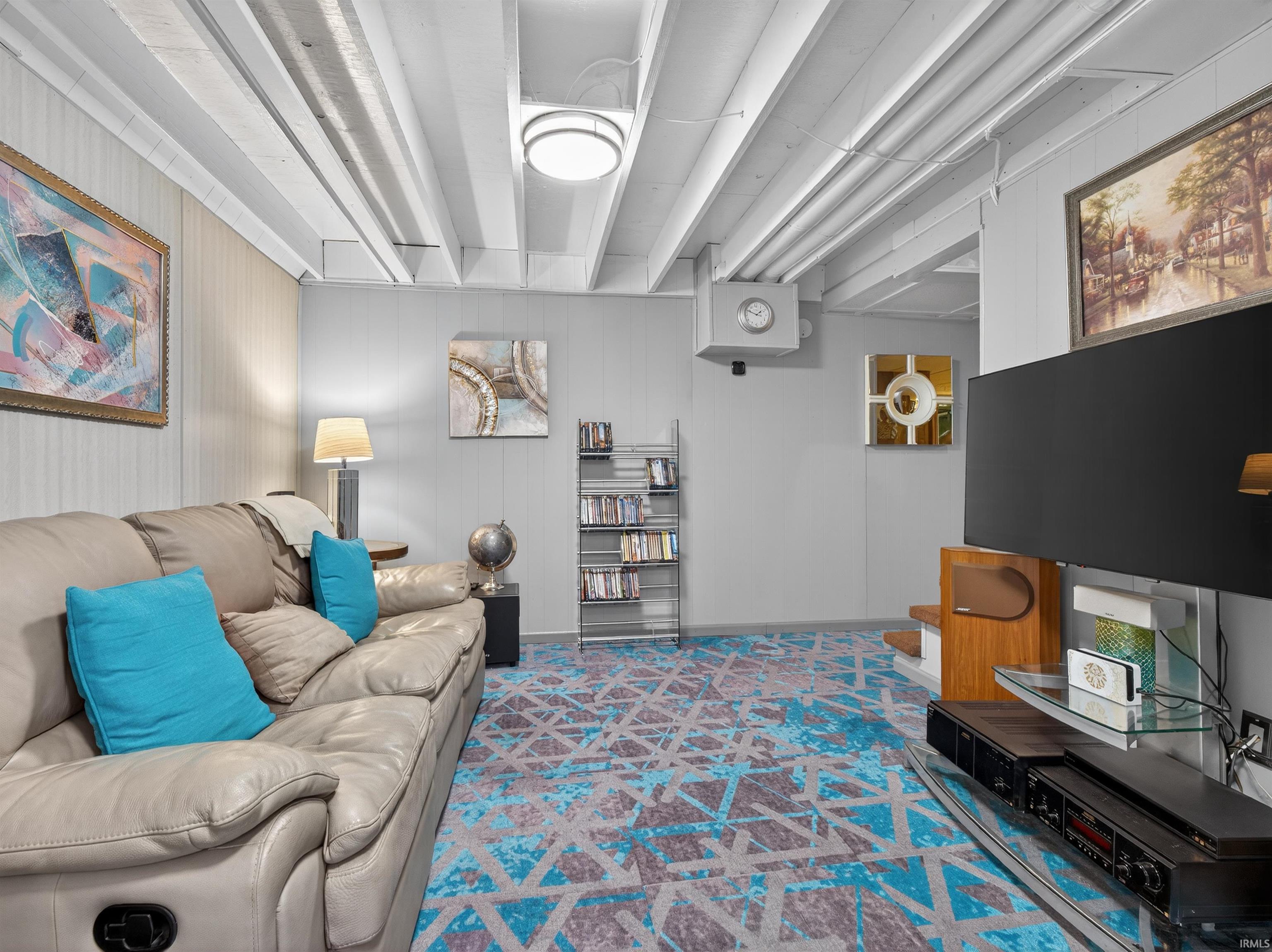 Carpeted living room featuring wood walls