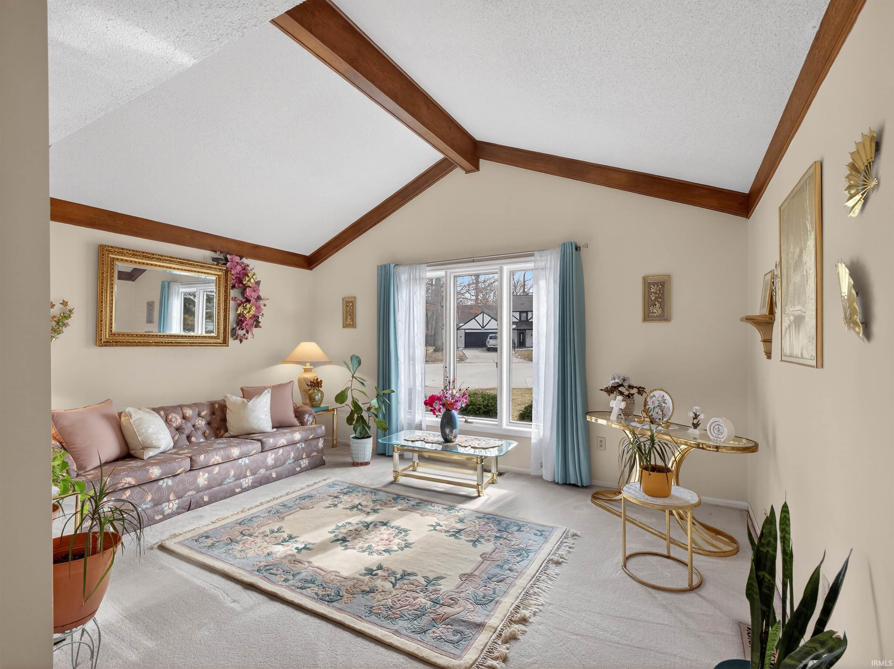 Living room featuring beam ceiling, carpet, and a textured ceiling