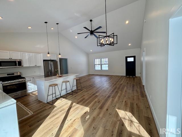 Kitchen with white cabinetry, stainless steel appliances, open floor plan, a breakfast bar area, and dark wood-style flooring