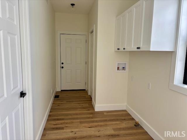 Laundry room featuring light wood finished floors, washer hookup, and cabinet space