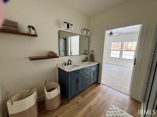 Full bathroom with double vanity, light wood-type flooring, and ceiling fan