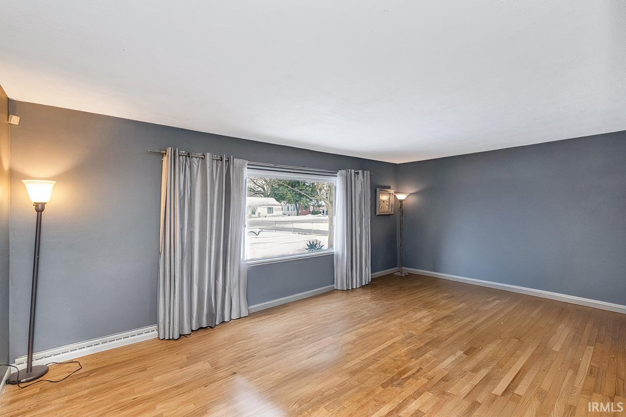 Unfurnished room with light wood finished floors and a baseboard heating unit