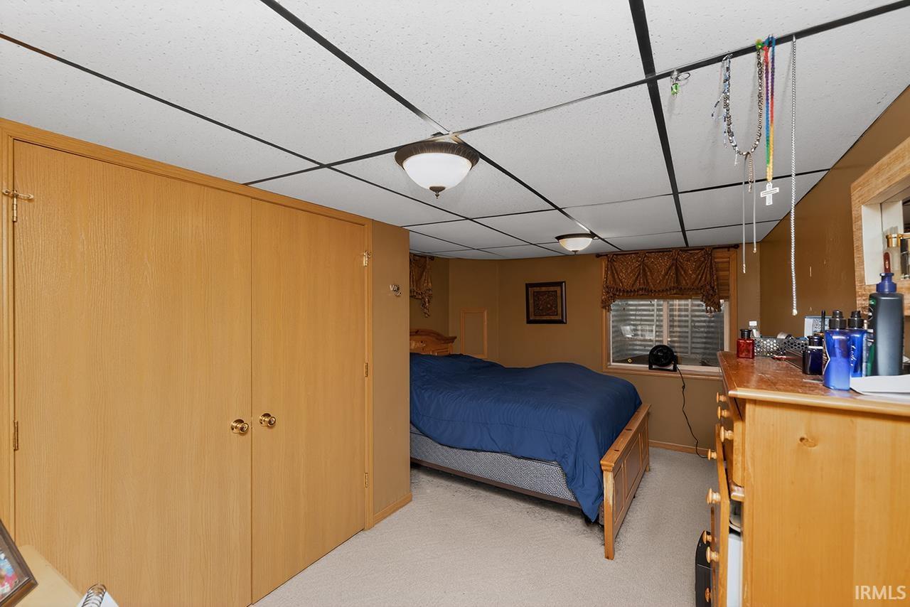 Bedroom featuring a drop ceiling, a closet, and light colored carpet