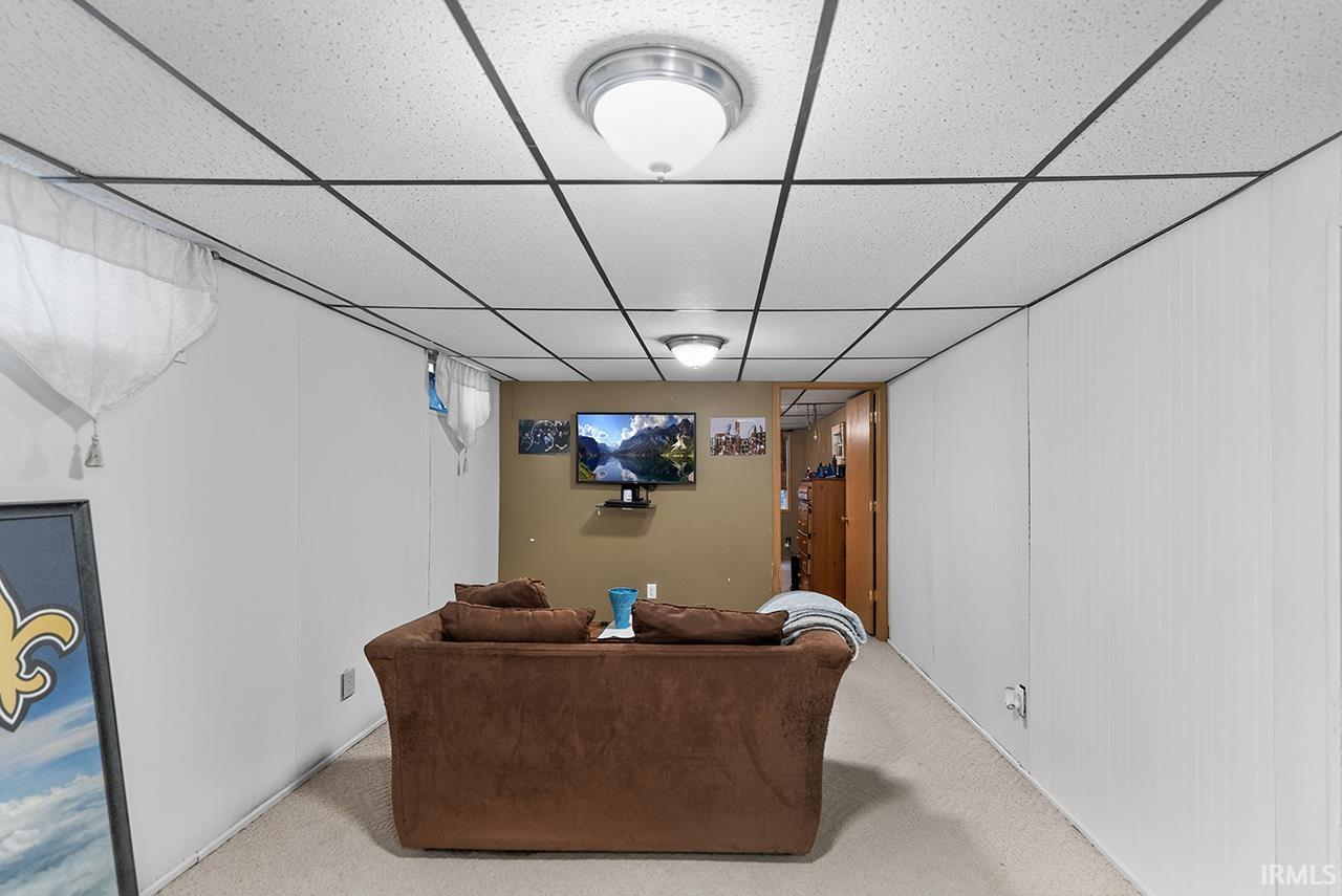 Living area with a drop ceiling and carpet flooring