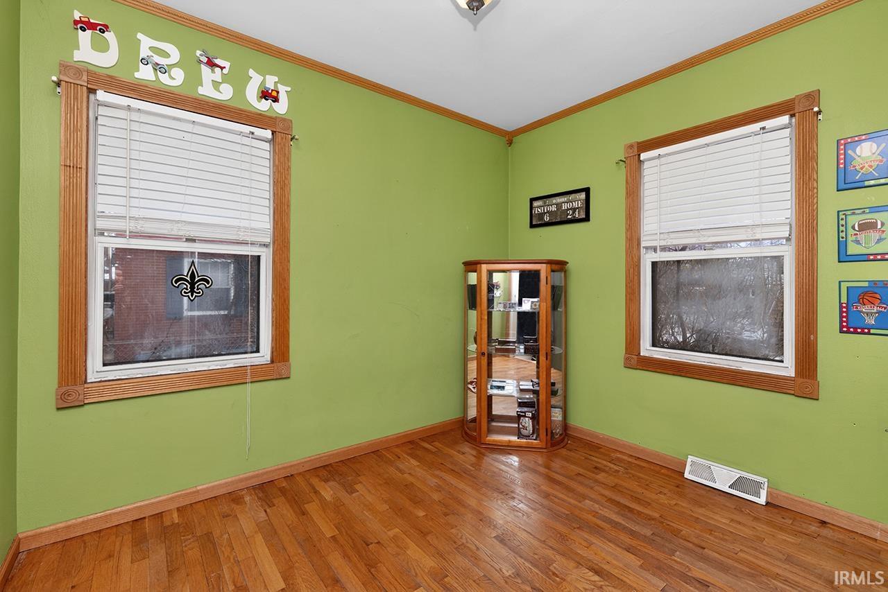 Unfurnished room with hardwood / wood-style flooring and crown molding