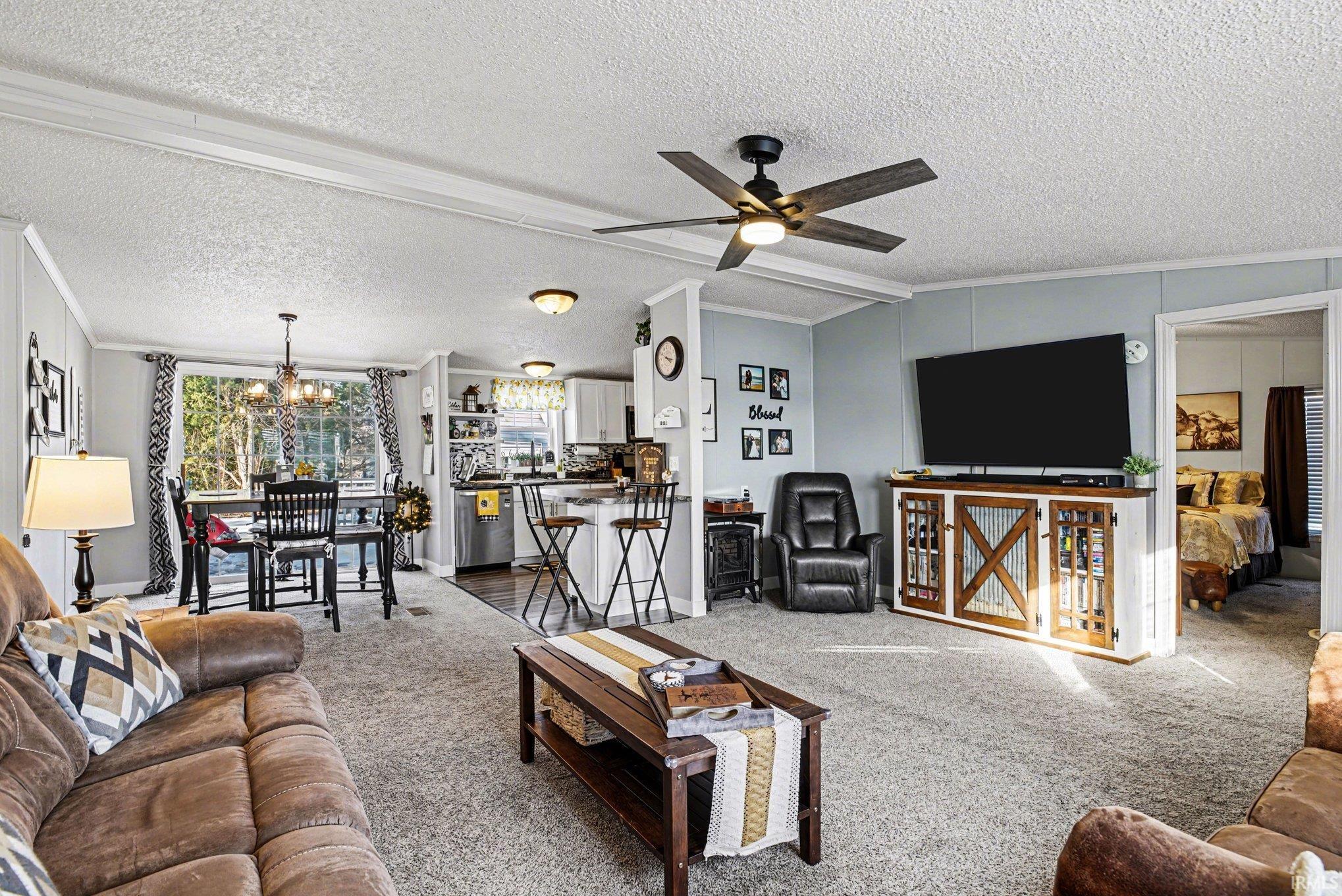 Living room with crown molding, carpet floors, and ceiling fan