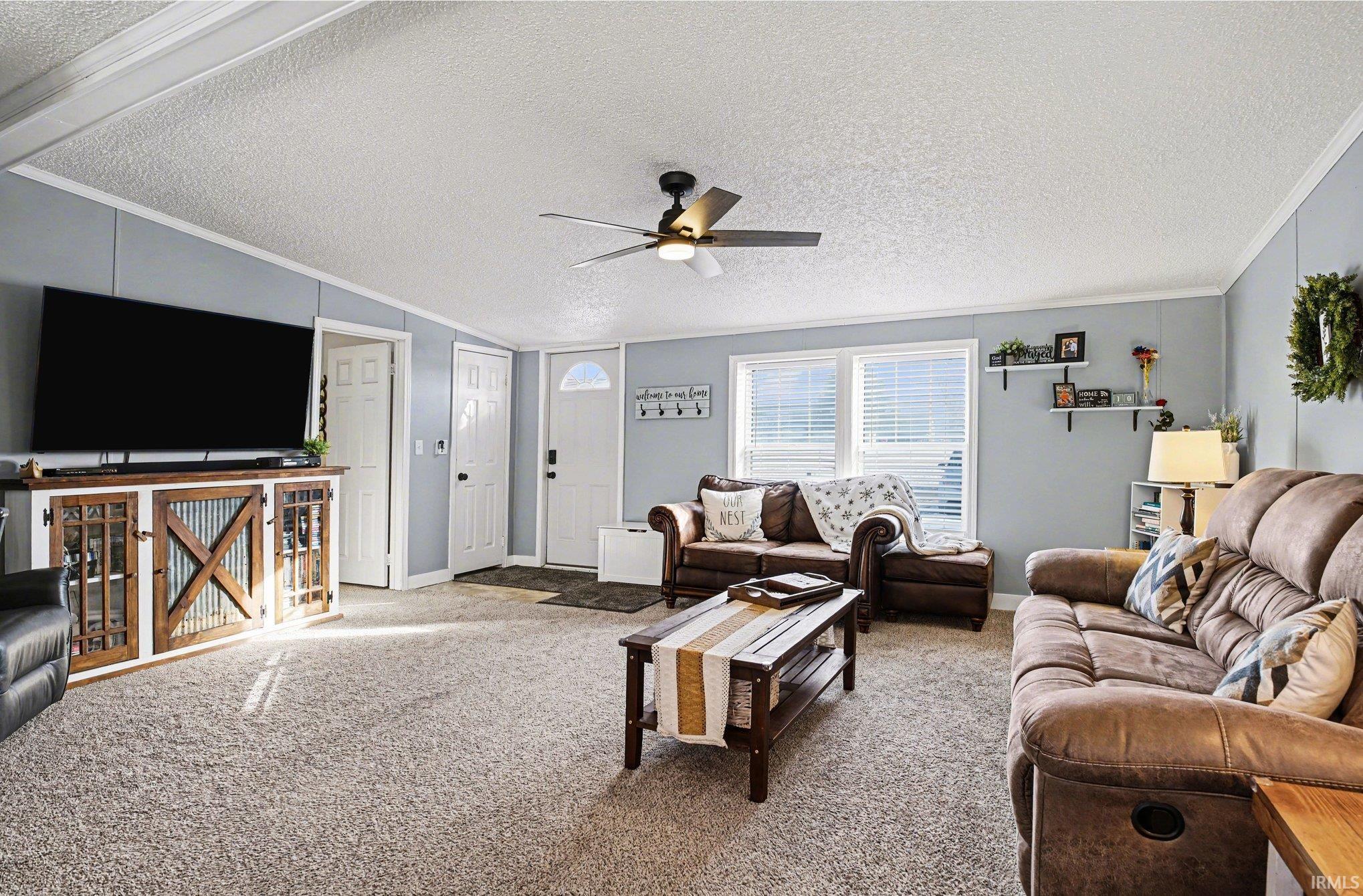 Living room with crown molding, ceiling fan, and carpet floors