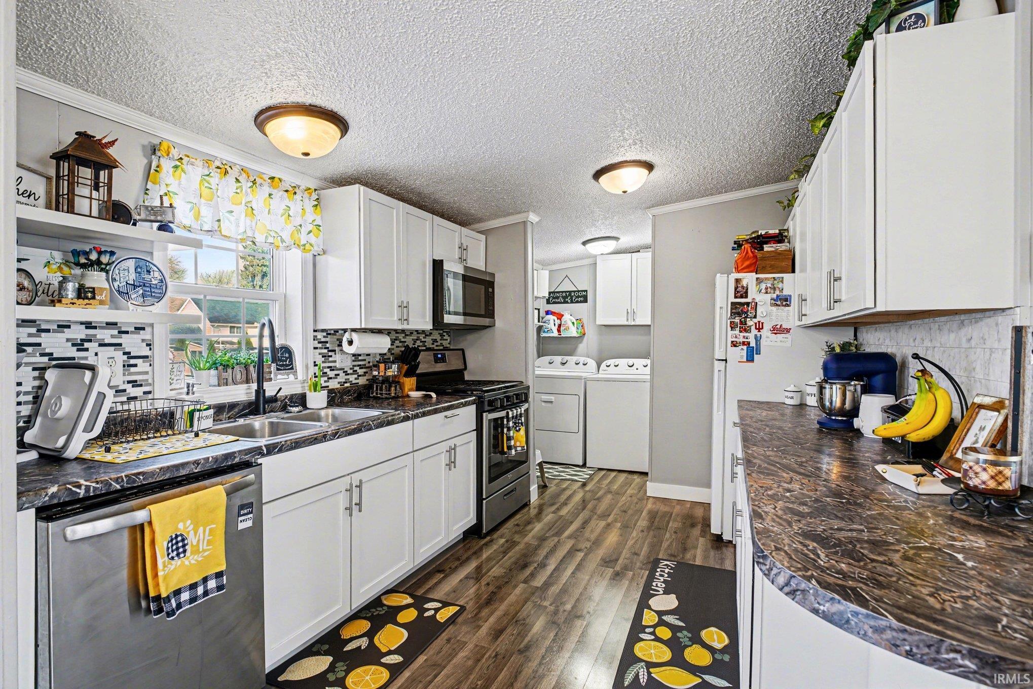 Kitchen with crown molding, dark countertops, tasteful backsplash, stainless steel appliances, and a textured ceiling
