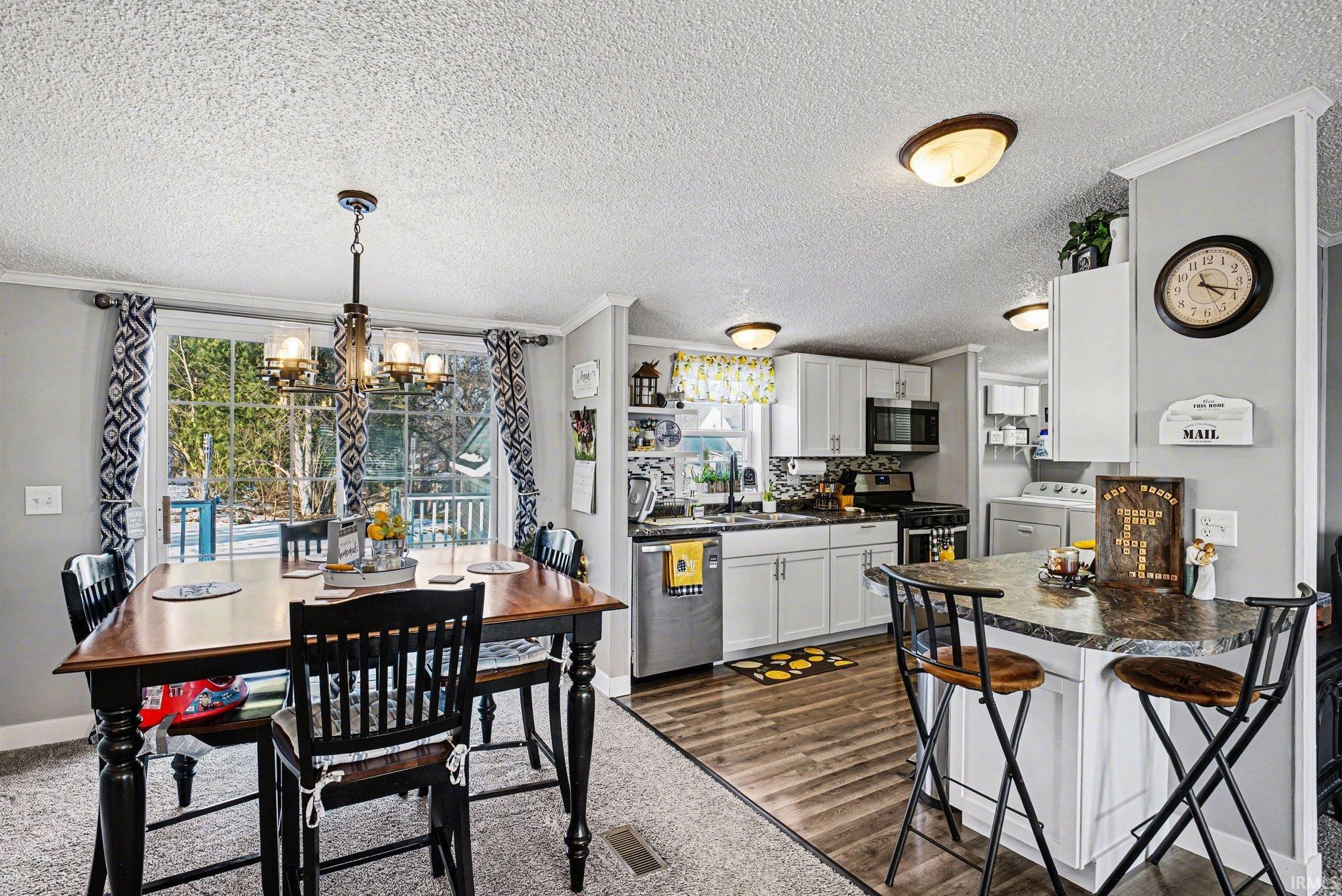 Dining area with ornamental molding, dark wood finished floors, a textured ceiling, and hanging lights