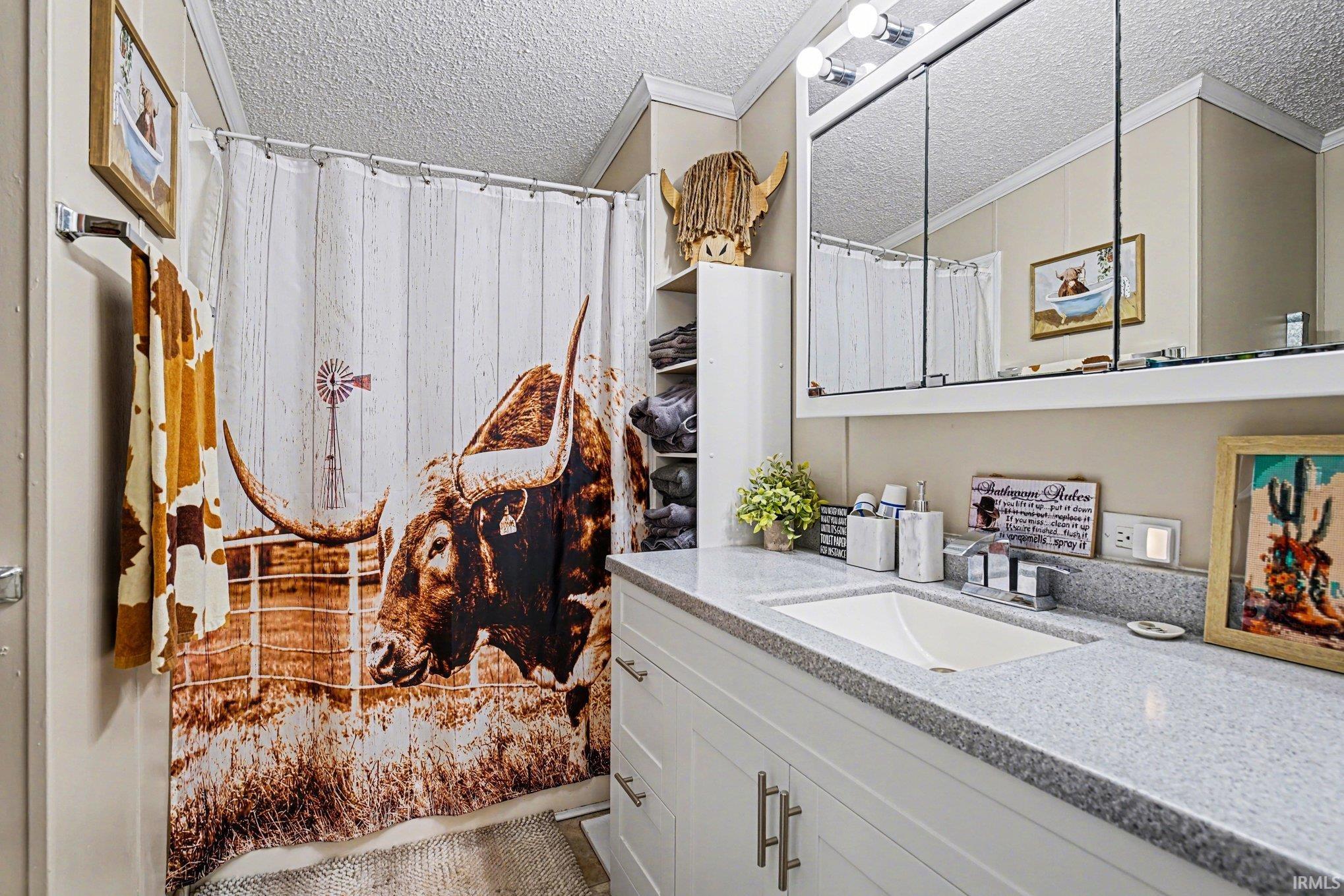 Full bath featuring vanity, a shower with shower curtain, crown molding, and a textured ceiling