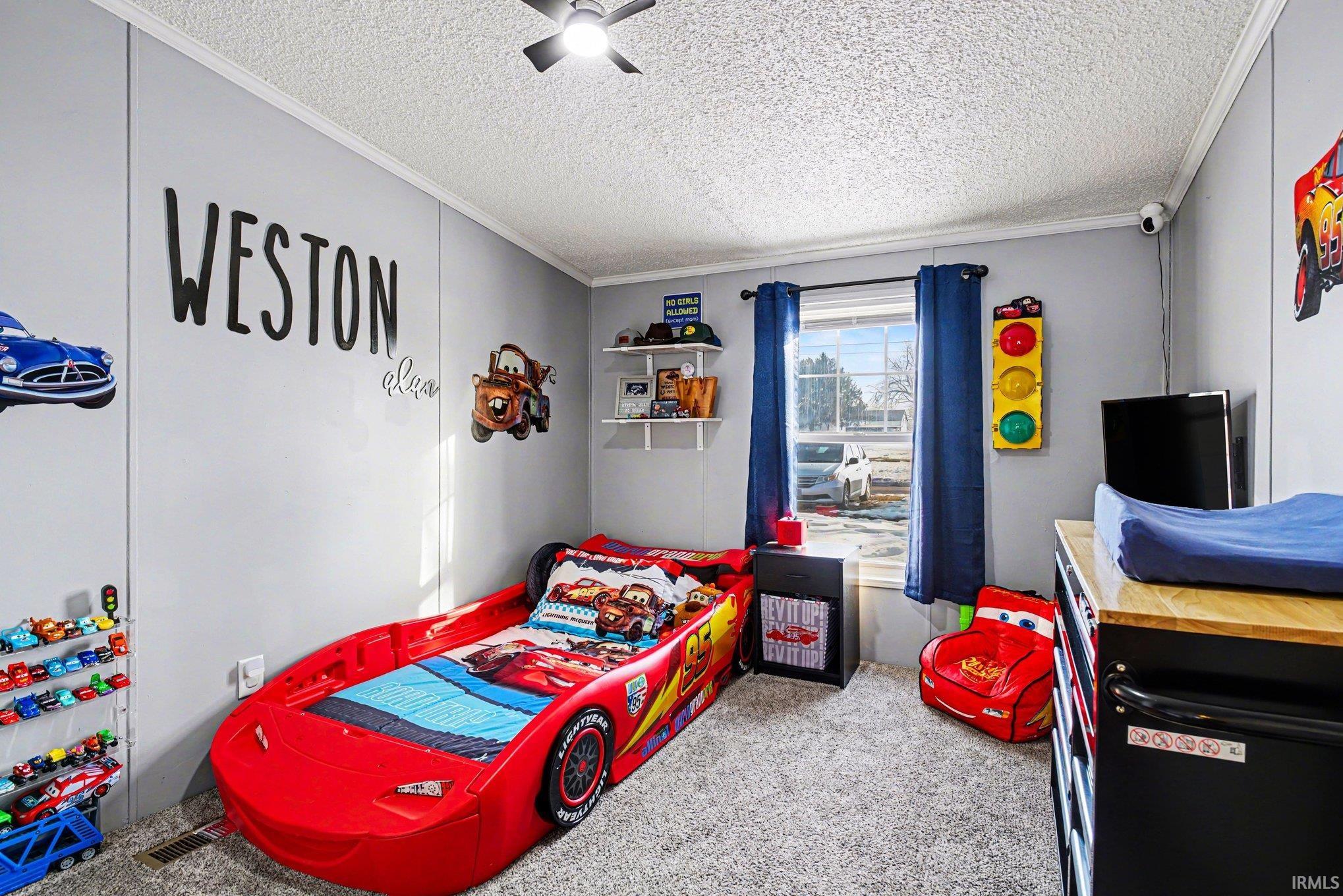 Bedroom featuring light carpet, a textured ceiling, ornamental molding, and a ceiling fan