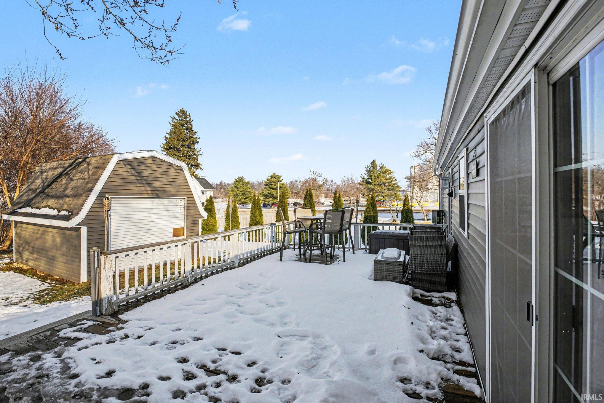 Snowy yard featuring a deck, an outbuilding, and outdoor dining space