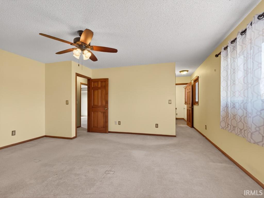 Unfurnished room featuring light colored carpet, a textured ceiling, and a ceiling fan
