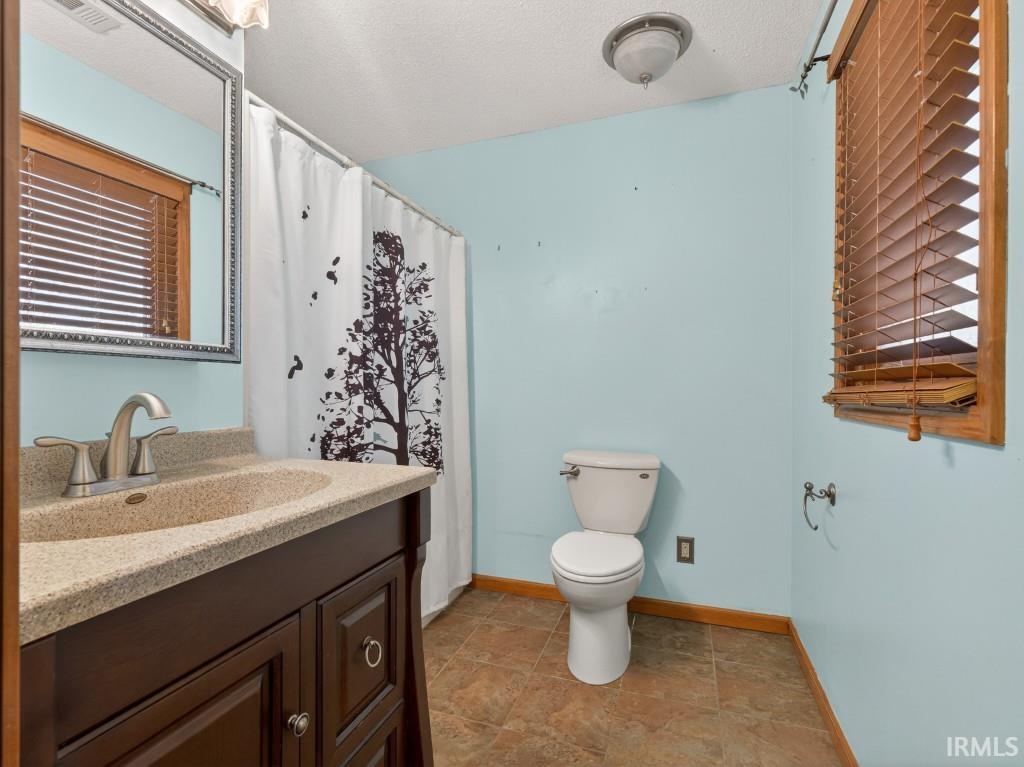 Full bath with vanity, a shower with curtain, and a textured ceiling