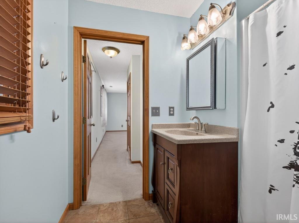 Bathroom with vanity, light carpet, and curtained shower