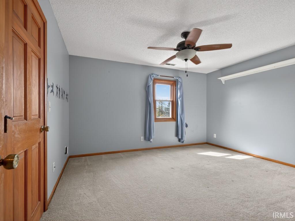 Spare room featuring light carpet, ceiling fan, and a textured ceiling