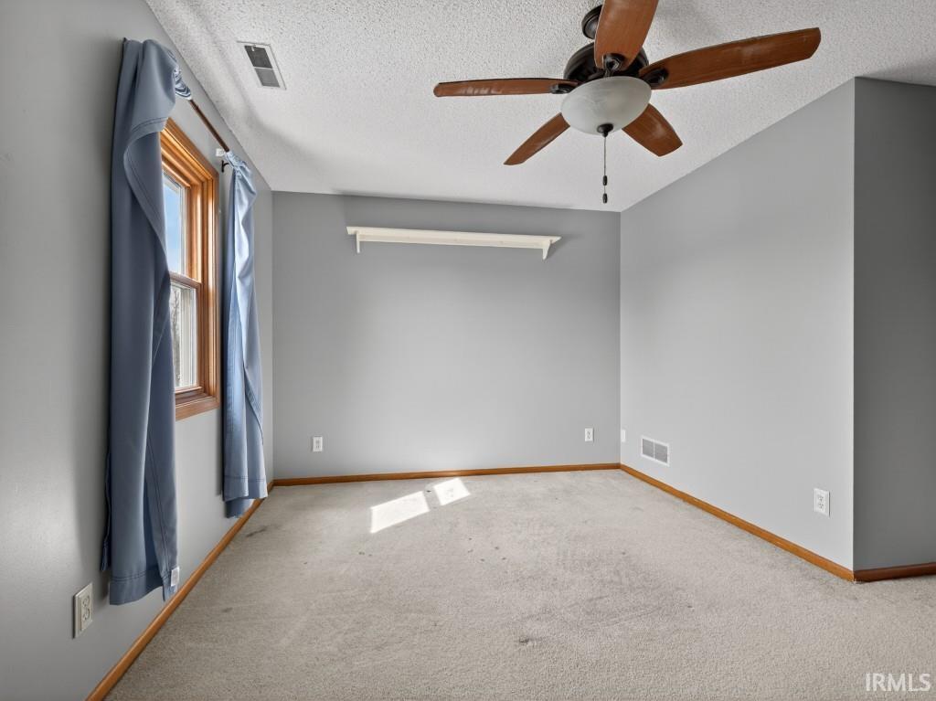 Spare room featuring carpet flooring, ceiling fan, and a textured ceiling