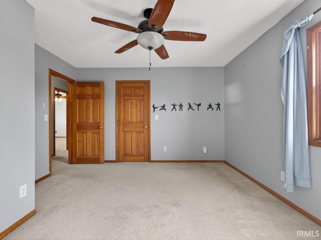Unfurnished bedroom with light carpet and ceiling fan
