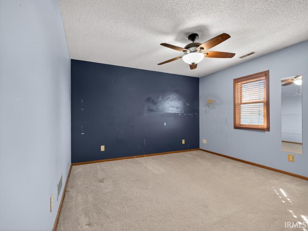 Empty room with carpet, a ceiling fan, and a textured ceiling