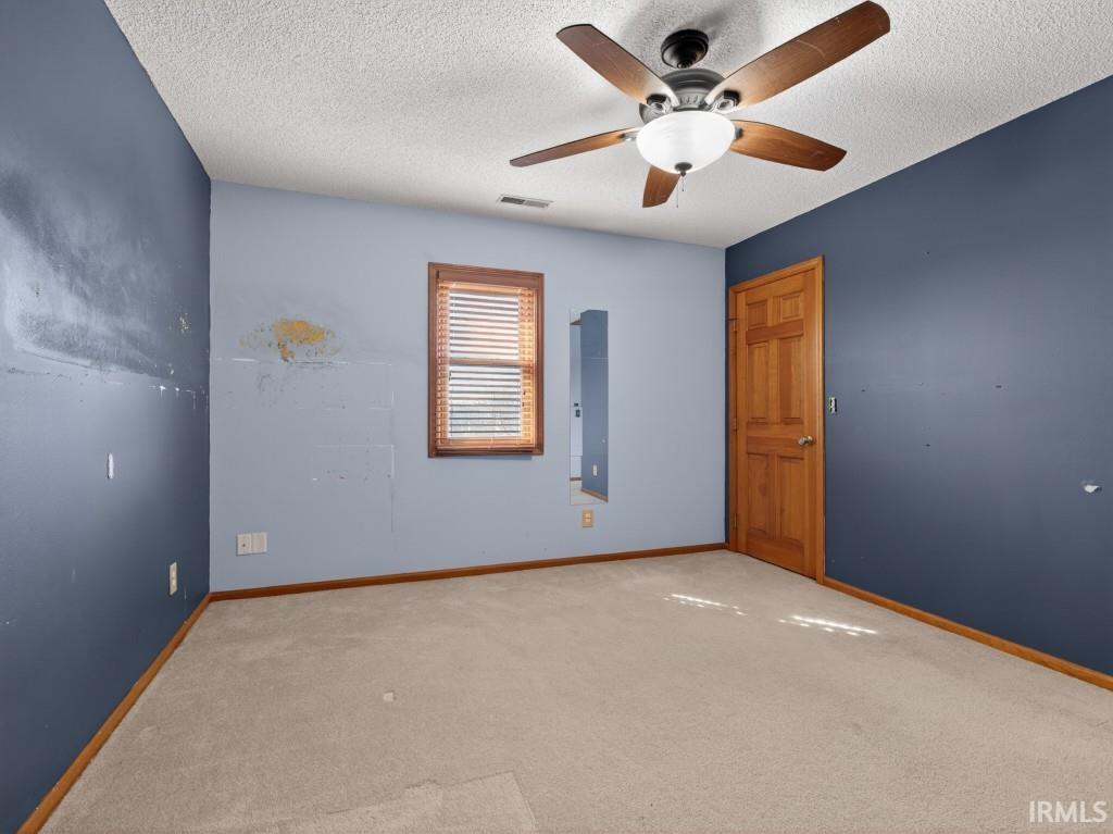 Unfurnished room featuring carpet, ceiling fan, and a textured ceiling