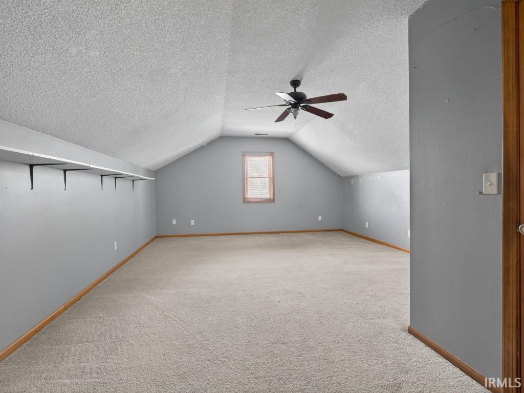 Bonus room with ceiling fan, light colored carpet, and a textured ceiling