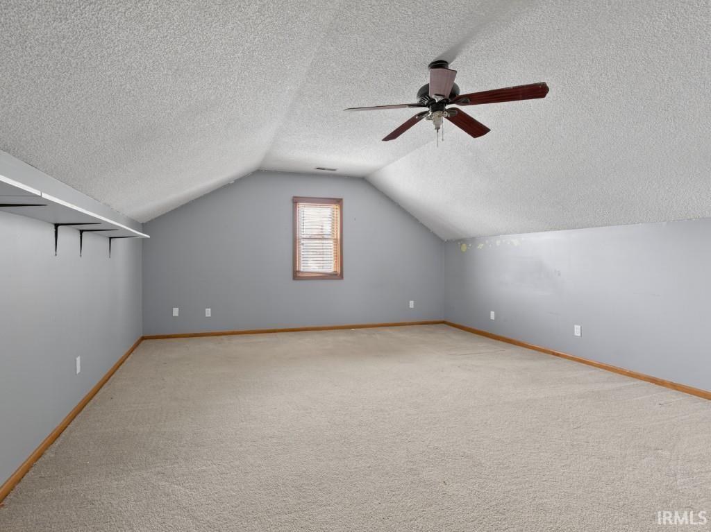 Bonus room with light carpet, a ceiling fan, and a textured ceiling