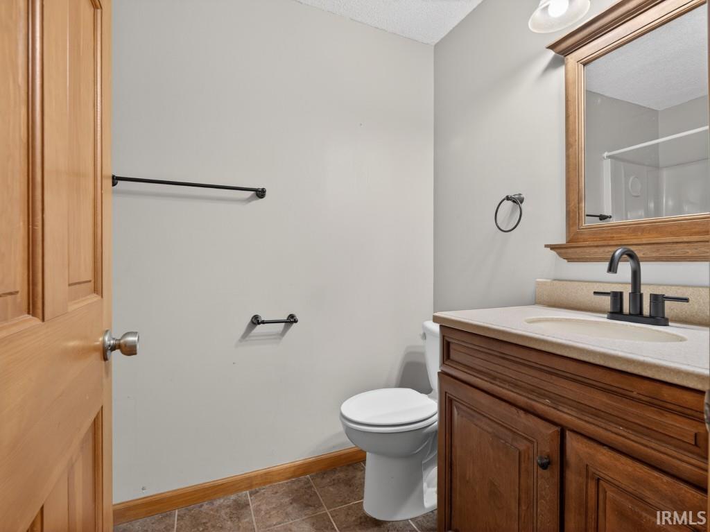 Bathroom with vanity, dark tile patterned floors, and a textured ceiling