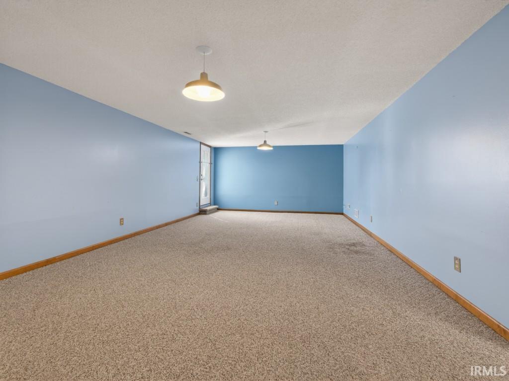 Carpeted spare room featuring baseboards and a textured ceiling