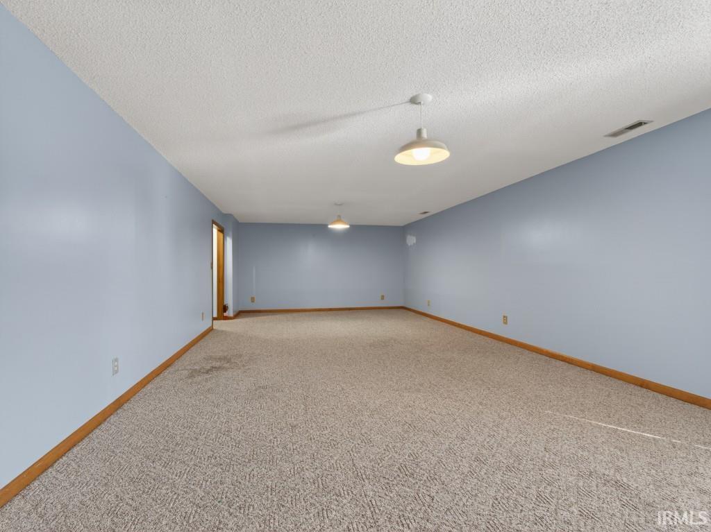 Empty room with carpet floors and a textured ceiling