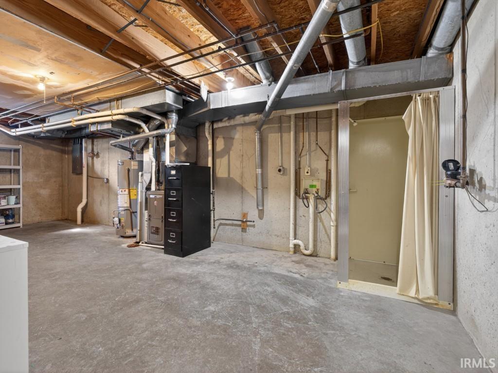 Unfinished below grade area with gas water heater, heating unit, washer / dryer, and electric panel