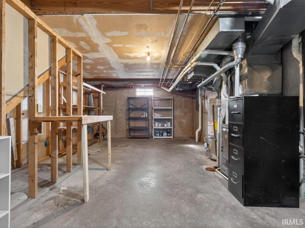 Unfinished below grade area featuring heating unit and water heater