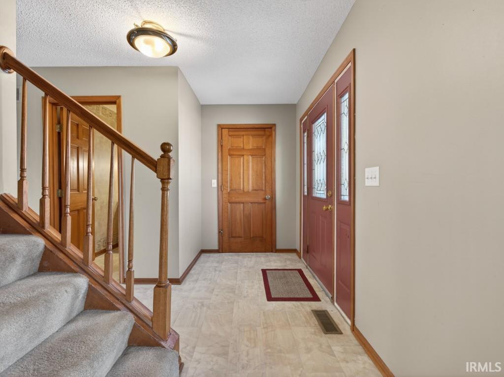 Foyer entrance featuring a textured ceiling and light floors