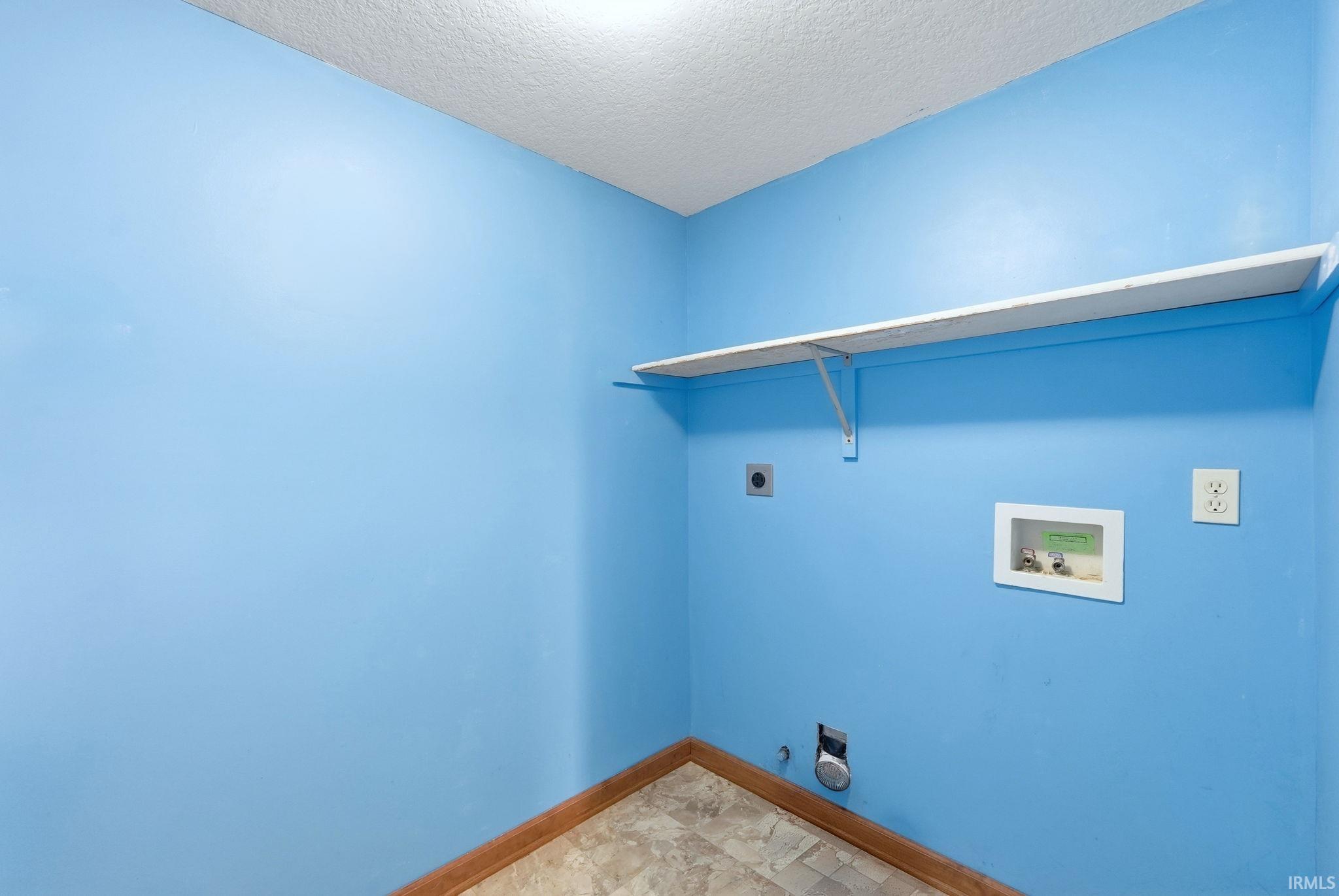 Laundry area featuring hookup for an electric dryer, a textured ceiling, and hookup for a washing machine