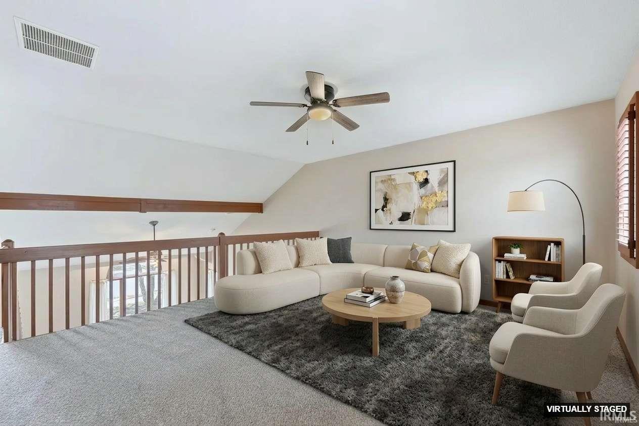Carpeted living room with ceiling fan and lofted ceiling