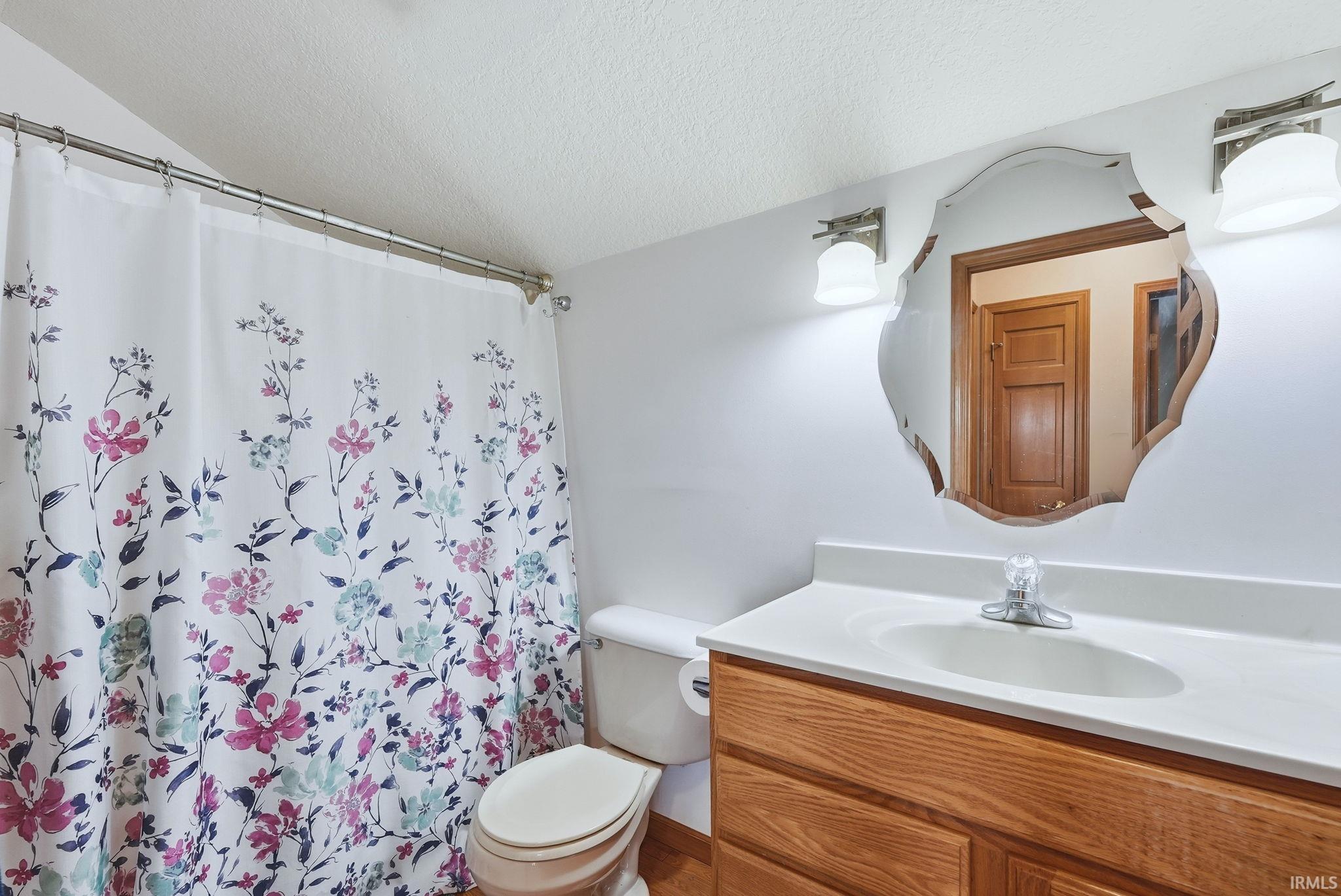 Bathroom with vanity, a textured ceiling, and a shower with curtain