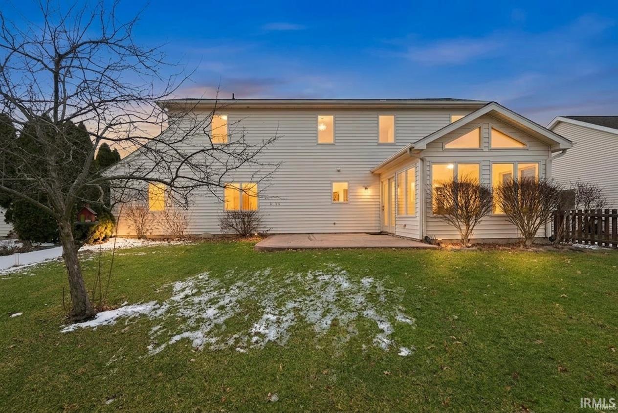 Back of property at dusk featuring a patio