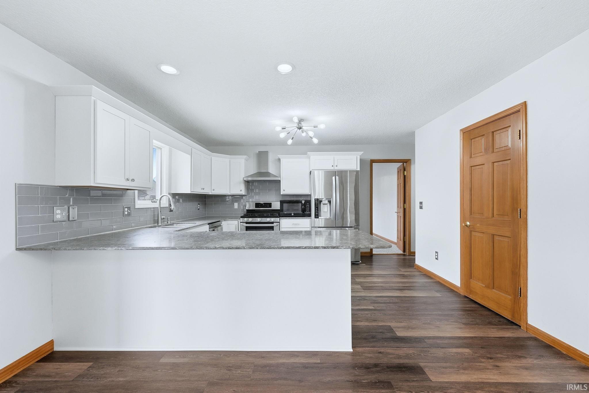 Kitchen with white cabinets, stainless steel appliances, and decorative backsplash