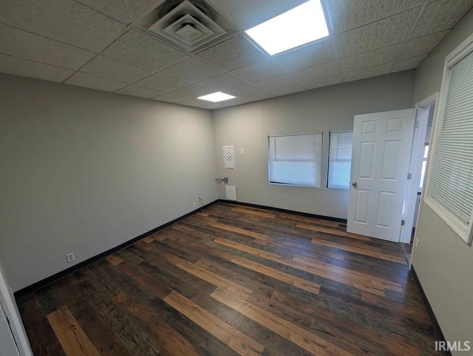 Unfurnished room featuring dark wood finished floors and a paneled ceiling