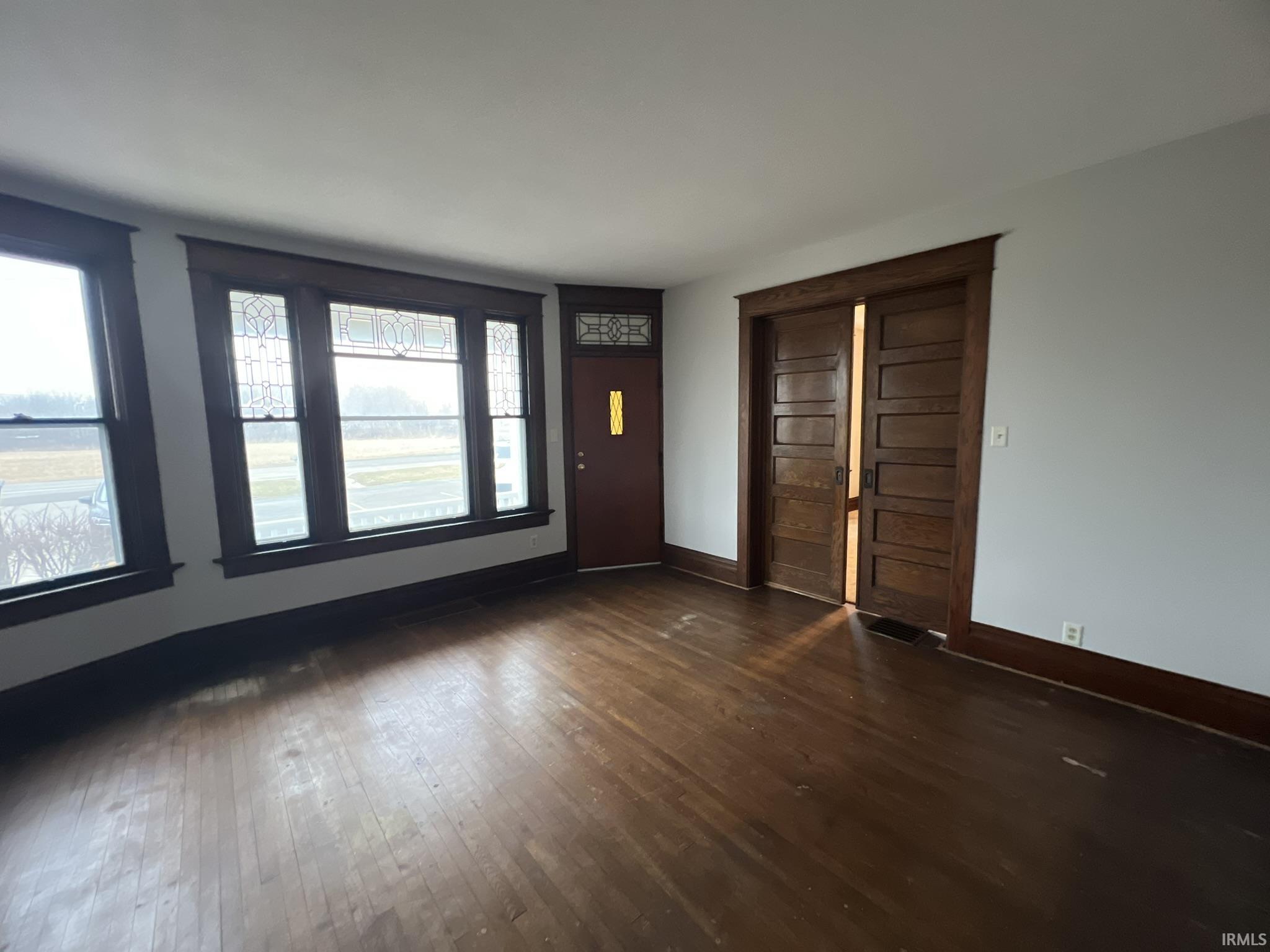 Foyer with dark wood-type flooring and baseboards