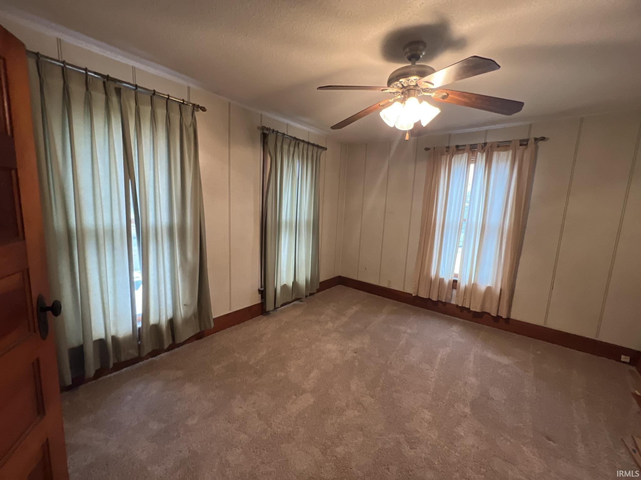 Empty room with a decorative wall, carpet flooring, and ceiling fan