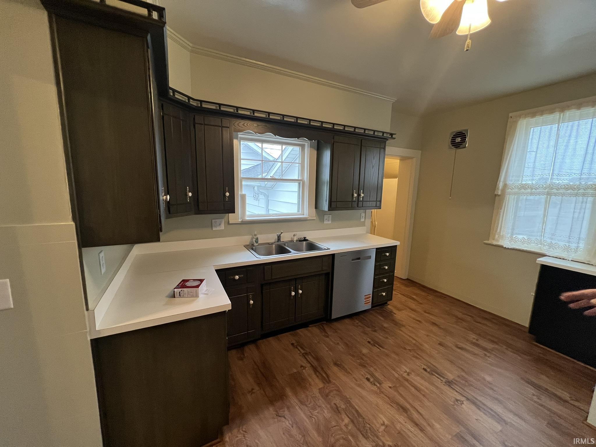 Kitchen with light countertops, stainless steel dishwasher, dark wood-type flooring, dark wood finish cabinets, and ceiling fan