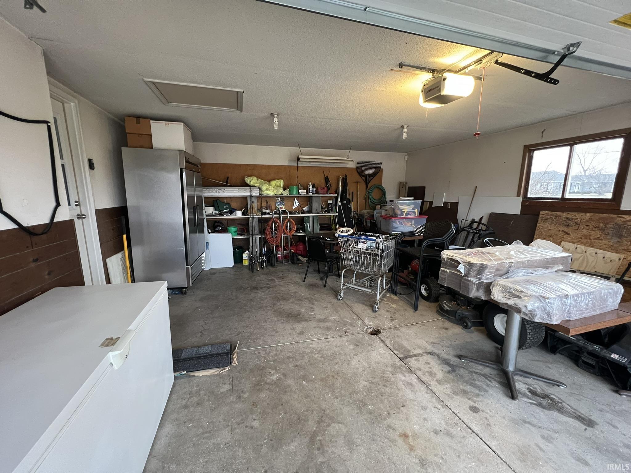 Garage featuring freestanding refrigerator and a garage door opener