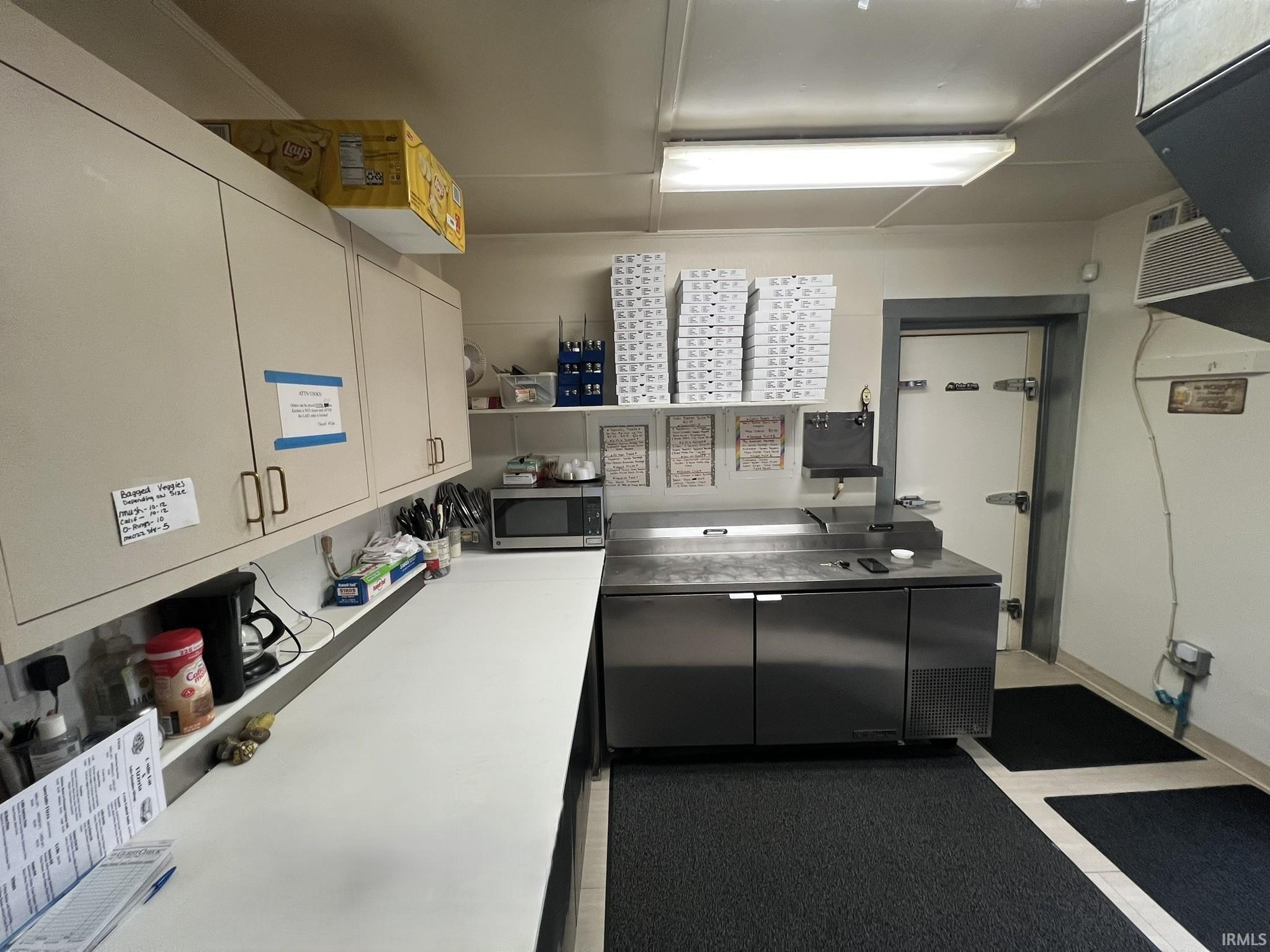 Kitchen featuring stainless steel microwave, light countertops, and a heating unit