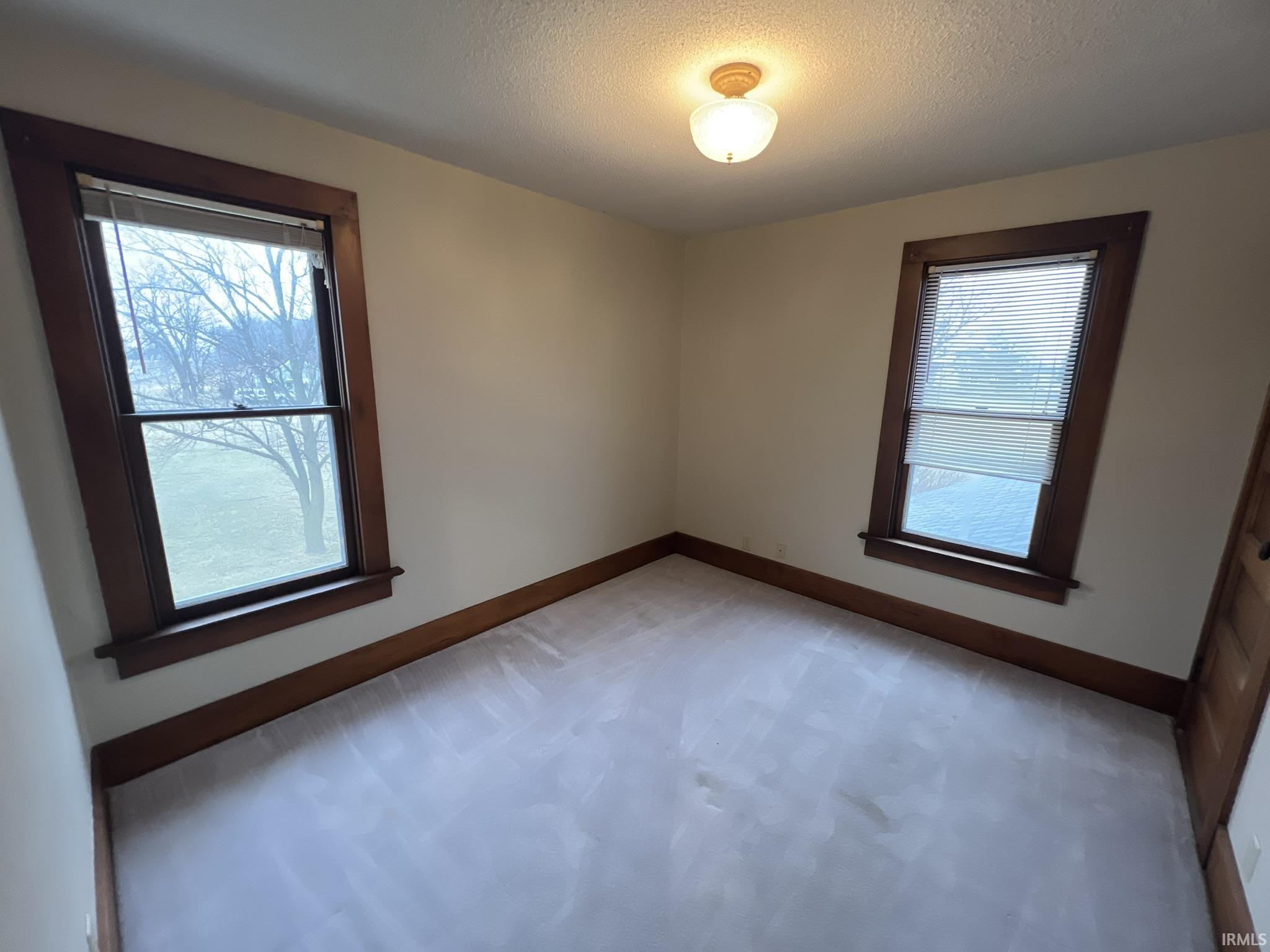 Unfurnished room with light carpet and a textured ceiling