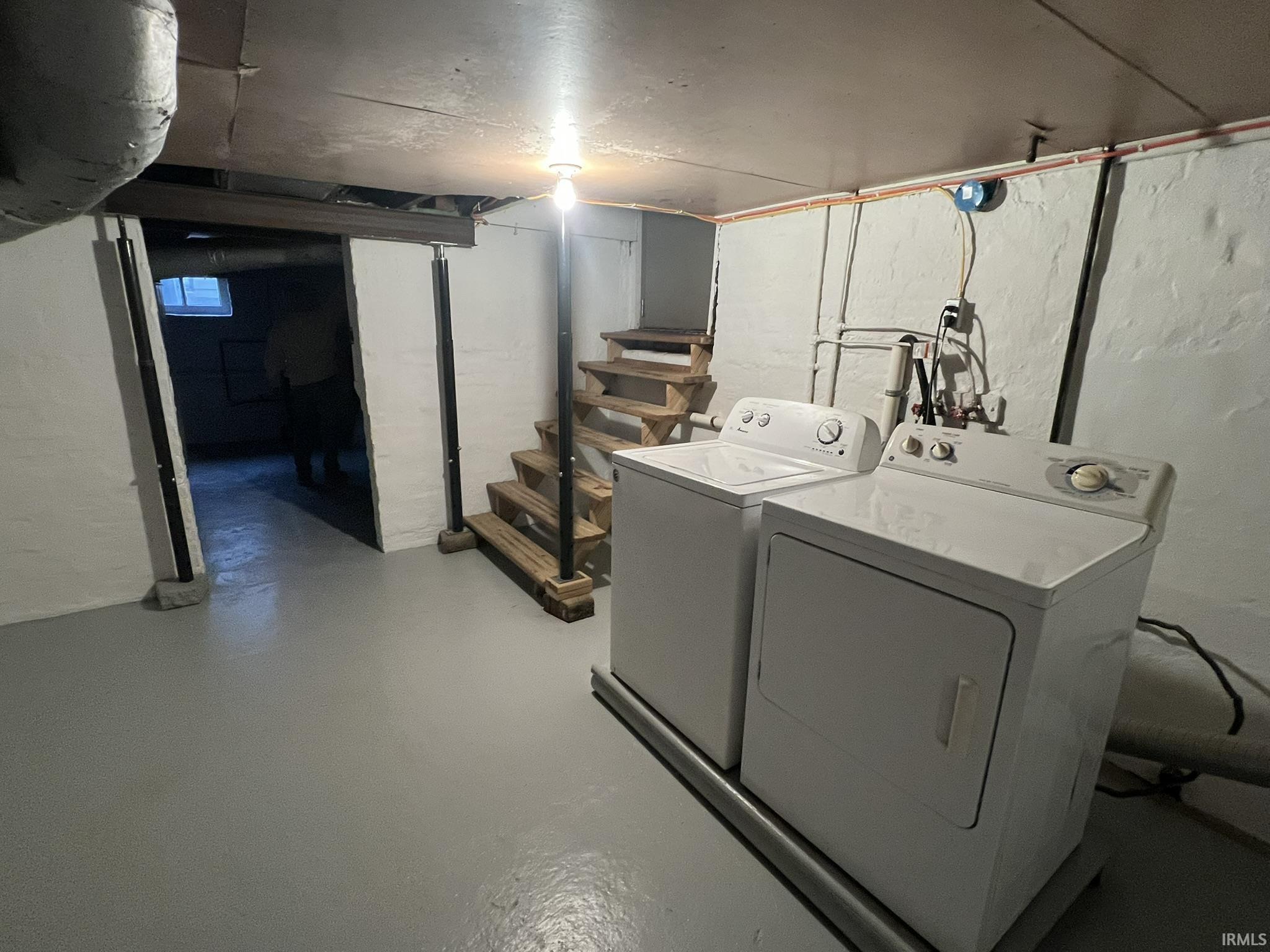 Laundry area featuring finished concrete flooring and separate washer and dryer