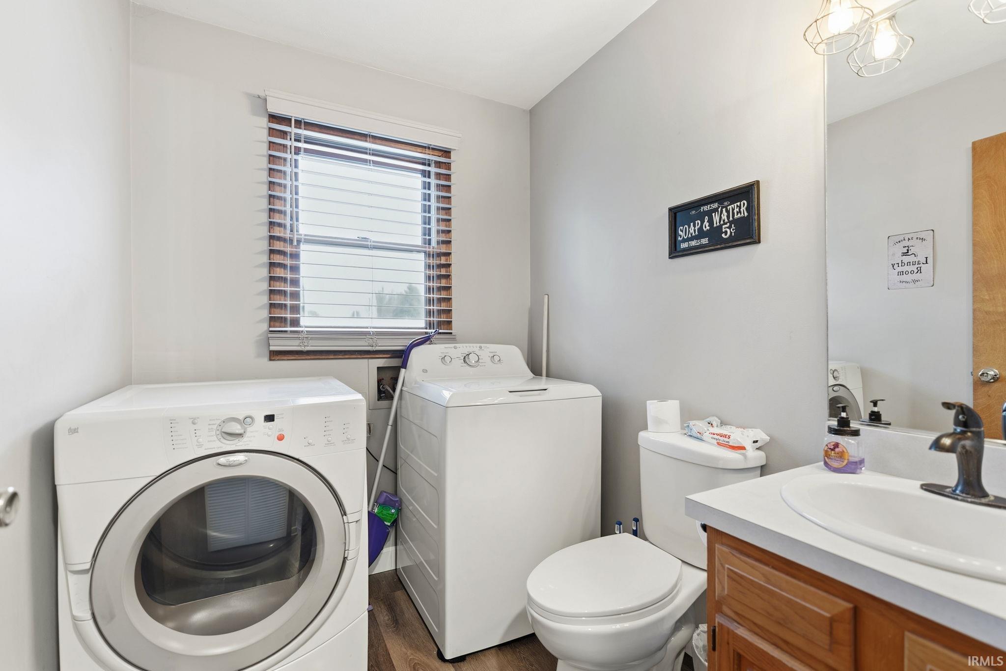 Half bath with vanity, dark wood-style flooring, and washing machine and dryer